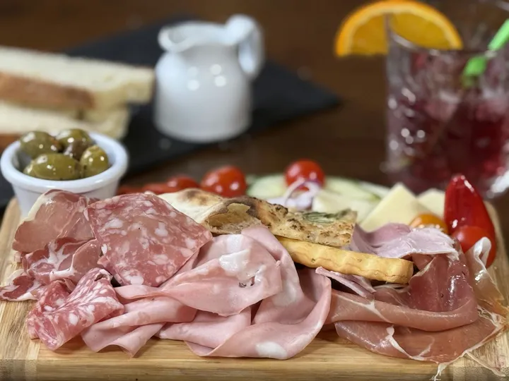 A charcuterie board with cured meats, cheese, olives and bread
